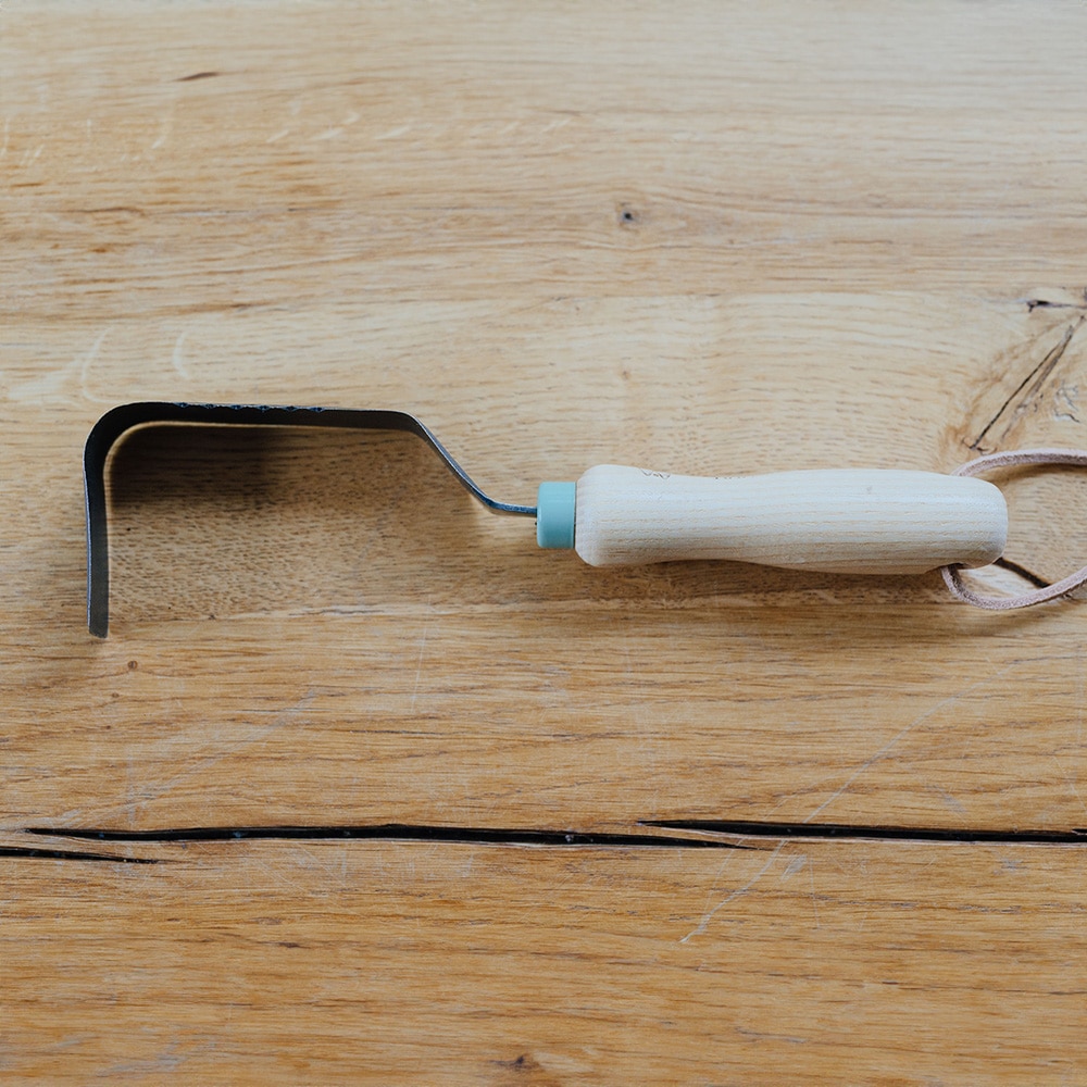 Unkrautfinger mit Wurzelsäge gnaz auf einem Holztisch