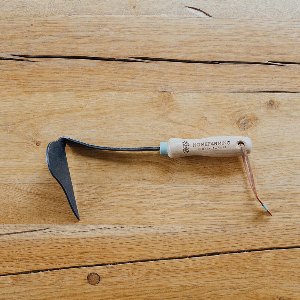 Unkraut-Sichelhacke auf Holztisch